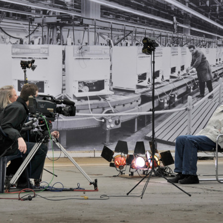 Ullabritt Horn vor der Kulisse der ehemaligen AEG-Produktion mit einem Gewerkschafter.